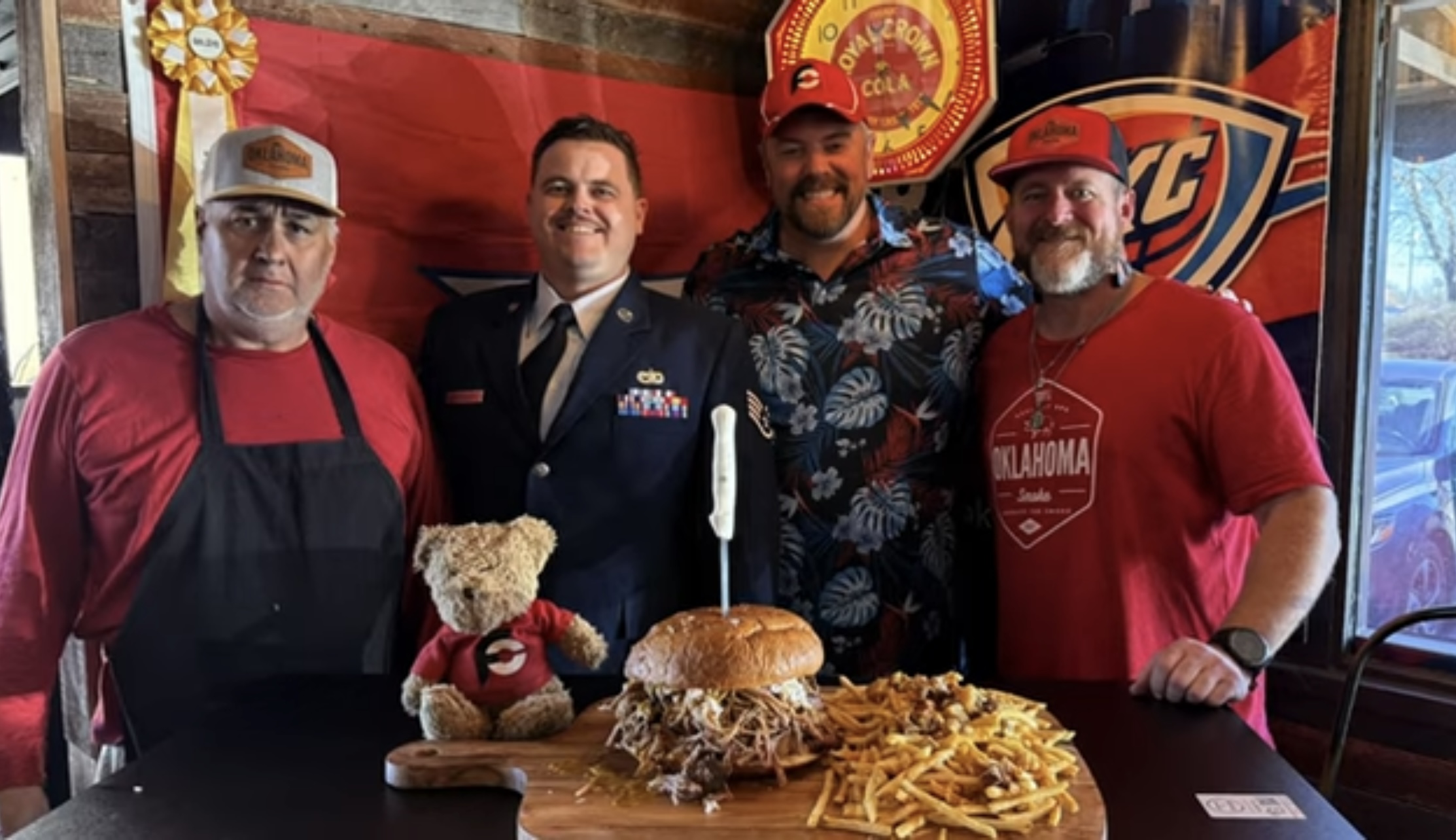 The founders of Oklahoma smoke BBQ taking a picture behind a table of BBQ food.