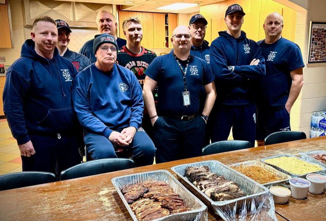 A group picture of a fire department eating Oklahoma smoke BBQ catering.