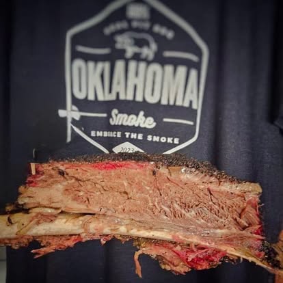 smoke-logo-meat - Oklahoma Smoke BBQ Cut brisket displayed Infront of a Oklahoma Smoke BBQ shirt.